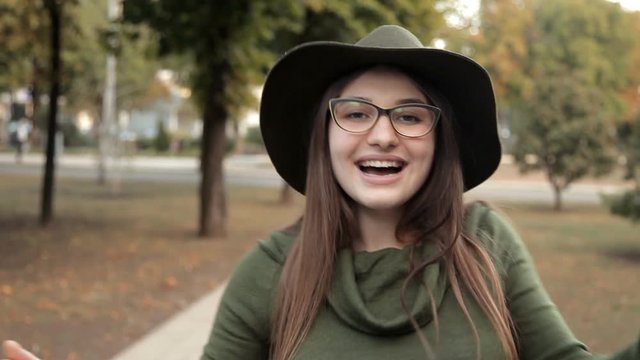 Beautiful young girl dancing in a park outside. Joy, autumn, a girl in a hat and glasses