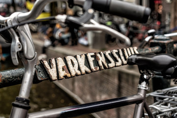 Fototapeta na wymiar Abgestelltes Fahrrad an Brücke mit antiker Beschriftung in Amsterdam 