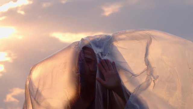 Slow Motion Shot Of A Female Isolated From Nature Wrapped In Plastic Outdoors At Sunset