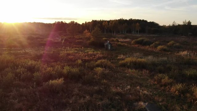 Wonderful sunset in autumn evening, beauty of nature, lens flare natural effect. Wooden hut in the middle of the meadow