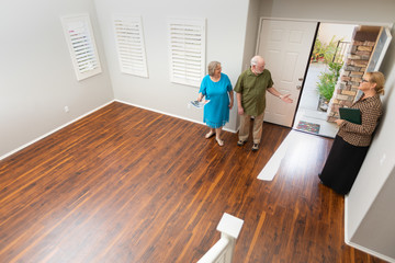 Female Real Estate Agent Showing Senior Adult Couple A New Home