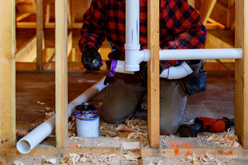 Plumbing contractor installing plastic PVC pipe in under the bathroom sink