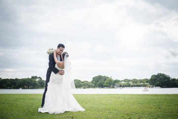 Happy smiling couple in wedding. Pretty Bride and handsome groom gorgeous posting in the nature.