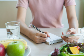 Dieting and calories control for wellness. Woman using smartphone calculate calories of food in...