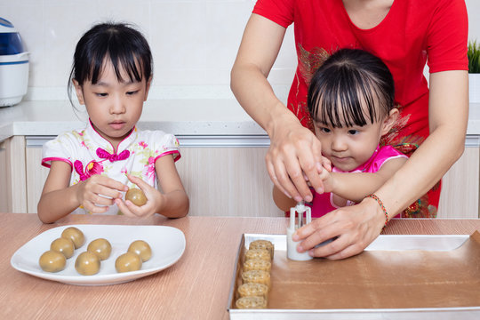 Asian Chinese mother and daughters making moon cake in the kitchen