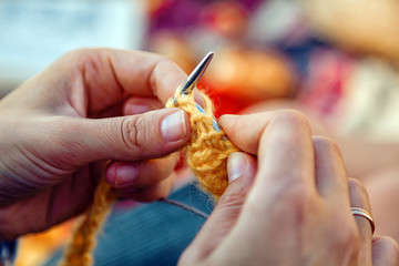 Concept of a freelancer work in the open air. Close up  of a young woman in a denim jacket knitting...