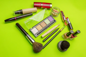 The composition of accessories, makeup cosmetics on a bright green background. Top view.   