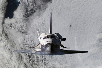 space ship shuttle flying near earth from the hurricane and massive clouds in atmosphere, image...