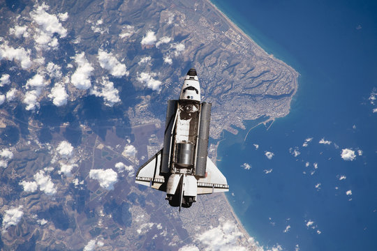 space ship shuttle flying near earth from the hurricane and massive clouds in atmosphere, image made of NASA photos f