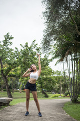 Young sport woman runner stretching body before run on track in the park.