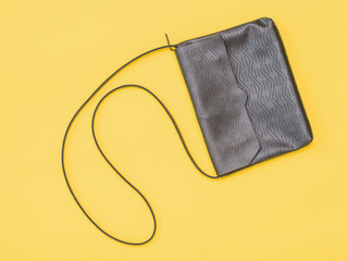 Leather black women bag on yellow bright background.