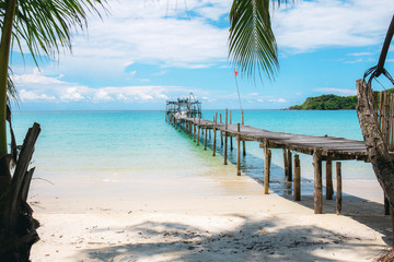 Bridge on beach with blue sky.
