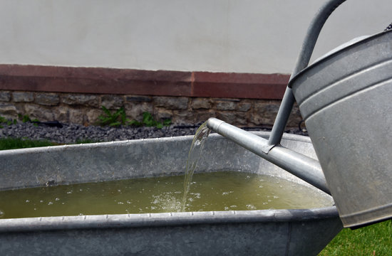 Fountain made out of metal watering can and old bathtub