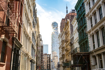 Naklejka premium Widok na zabytkowe budynki na skrzyżowaniu ulic Greene i Canal w SoHo Manhattan, Nowy Jork z promieniami słońca świecącymi w tle