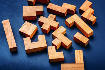 Different geometric shapes wooden blocks on a dark background. Creative, logical thinking and problem solving concept