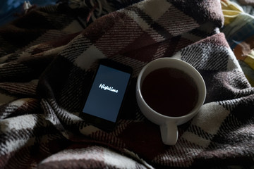 nighttime text om phone in bed sleeping concept with cup of tea idea f