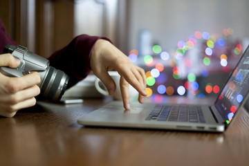 young male photographer holding a camera and prcessing his photos on laptop in the studio f