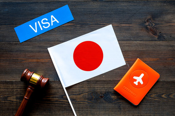 Visa to Japan concept. Text visa near passport cover and japanese flag, hammer on dark wooden...