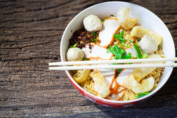 Noodles in bowl on wooden background, selective focus. Asian meal on a table, junk food concept