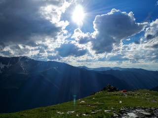 Tourist tent in mountains in the summer. Majestic light and rays in the mountains landscape....