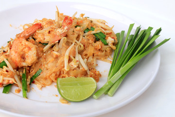 Pad Thai, stir-fried rice noodles with shrimp in white plate with slide lemon and green vegetable. The one of Thailand's national main dish. the popular food in Thailand. Thai Fried Noodles