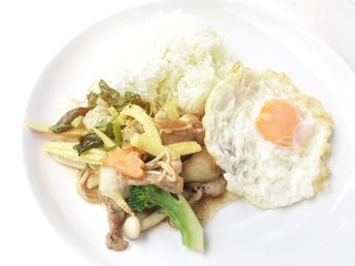 Stir fry chicken, sweet peppers, corn, broccoli, sweet basil and green beans with rice and fried egg in ธhai style in white dish on white background. Thai style food.