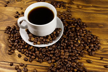 Cup of coffee and roasted coffee beans on wooden table
