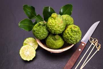 Bergamot, kaffir lime and kaffir lime leaf with basket and knife  on dark background