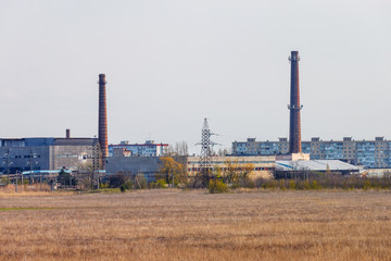 Fototapeta na wymiar Two industrial brick chimney in the manufacturing area with residential buildings in the background