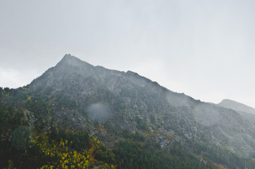 Fototapeta premium The rainy view of the granite mountain peaks under the overcast sky in the fall season. 