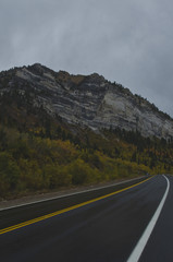 Fototapeta premium The wet road on mountain side under the rocky granite peaks in utah. 