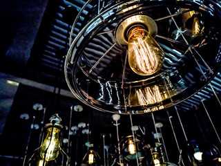 Tungsten orange light bulb hanging on the inside of the building with a black iron fence around,Lighting in buildings with multi-colored electric lamps,soft focus.