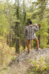 A hunter man staying in a forest and holding a gun on his shoulder