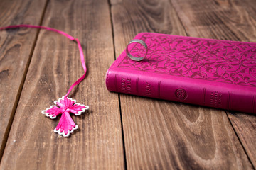 a ring on the bible and cross on wooden background