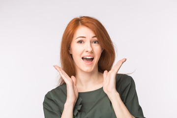 Surprised redhead young woman on white background