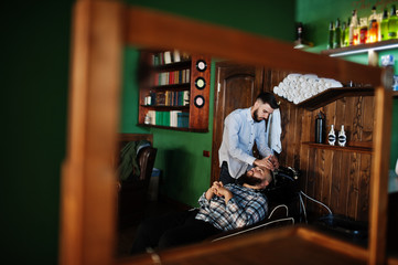Fototapeta na wymiar Handsome bearded man at the barbershop, barber at work. Washing head.