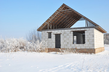 House construction in winter. Unfinished home roofing metal tiles construction. Roofing Construction in Winter.