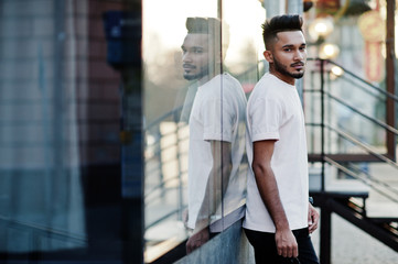 Stylish indian beard man at pink t-shirt. India model posed outdoor at streets of city against mirror of window.