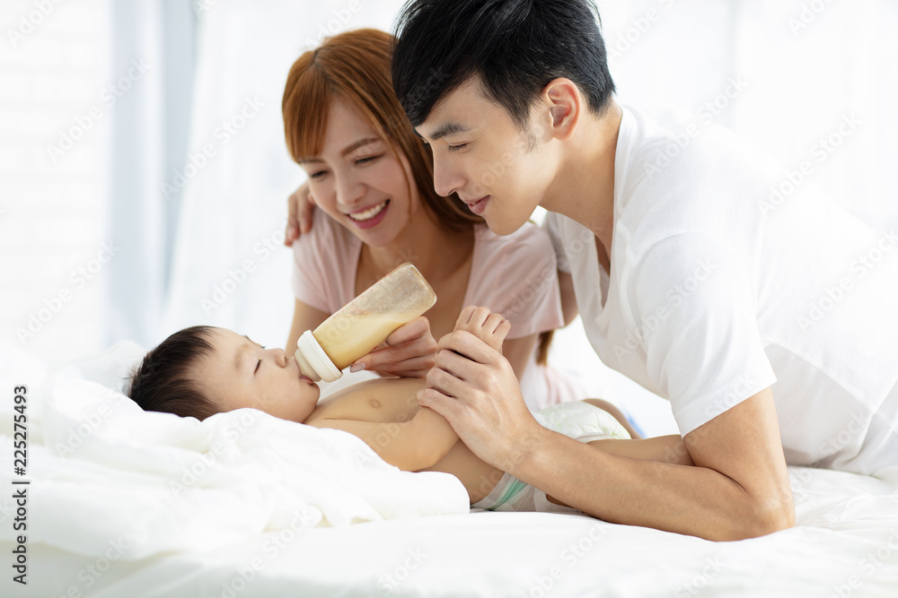 Wall mural happy father and mother feeding baby from bottle