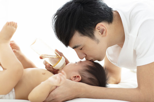 happy father feeding baby from bottle