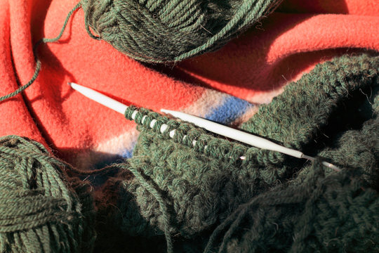 homemade hobby in a cozy setting/ Skeins of wool yarn and knitting needles on a plaid top view