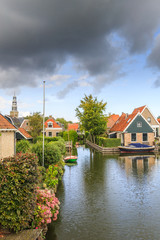 Fototapeta premium Yndyk, Hindeloopen, province of Friesland, municipality Súdwest-Fryslân, Netherlands, september 3, 2017: View to houses and boats at canal Yndyk seen from bridge at Nieuwe Weide