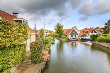 Fototapeta na wymiar Yndyk, Hindeloopen, province of Friesland, municipality Súdwest-Fryslân, Netherlands, september 3, 2017: View to houses and boats at canal Yndyk seen from bridge at Nieuwe Weide
