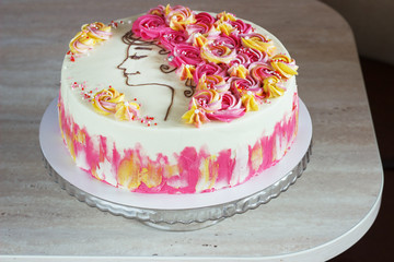 Festive cake with cream flowers and a girl face on a light background