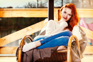 Atractive red-haired woman resting sitting on Rocking chair in f