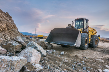 Excavators and heavy machinery in the works of stone movement in a quarry stone extraction for its...