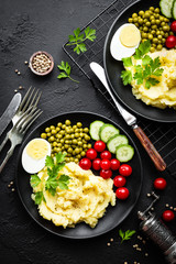 Mashed potato with green peas, tomatoes and boiled egg. Potato puree on plate with vegetables and egg