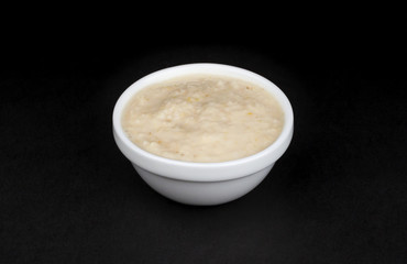 Horseradish sauce in bowl isolated on black background