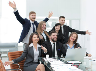 business team with their hands up and voting for decision-making near the desk