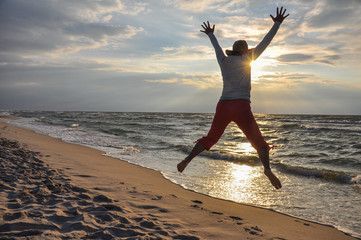 woman jumping on the beach - obrazy, fototapety, plakaty